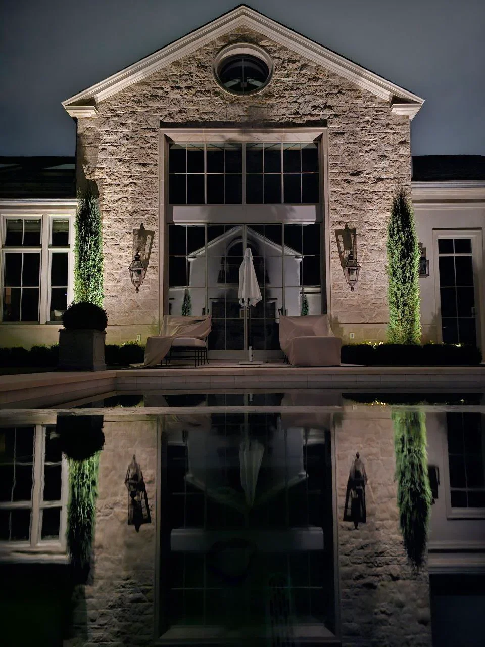 Nighttime view of stone house with architectural uplighting and landscape illumination