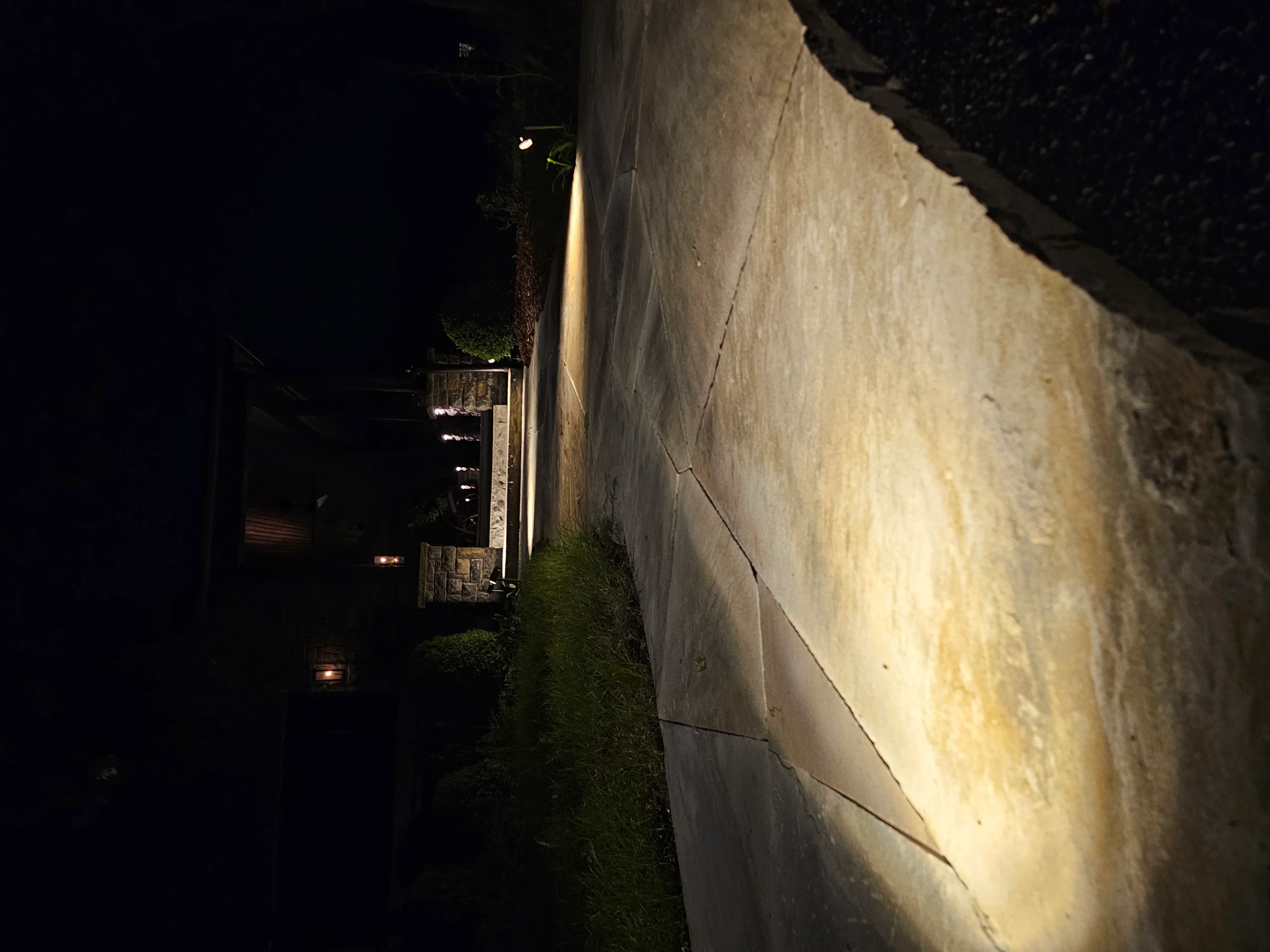 Warm LED uplighting on residential exterior wall at night with landscape lighting