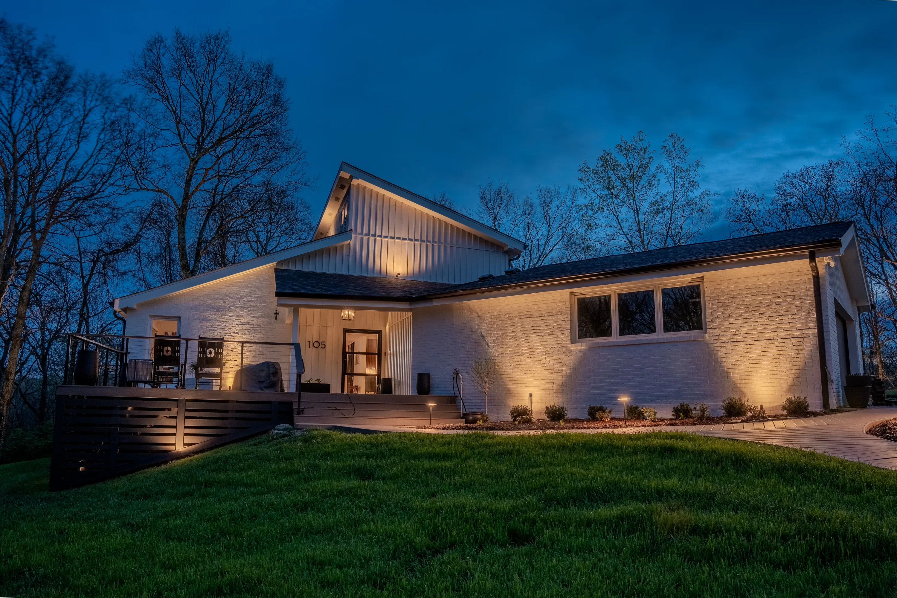 Modern home exterior with warm LED accent lighting on brick and roof at dusk