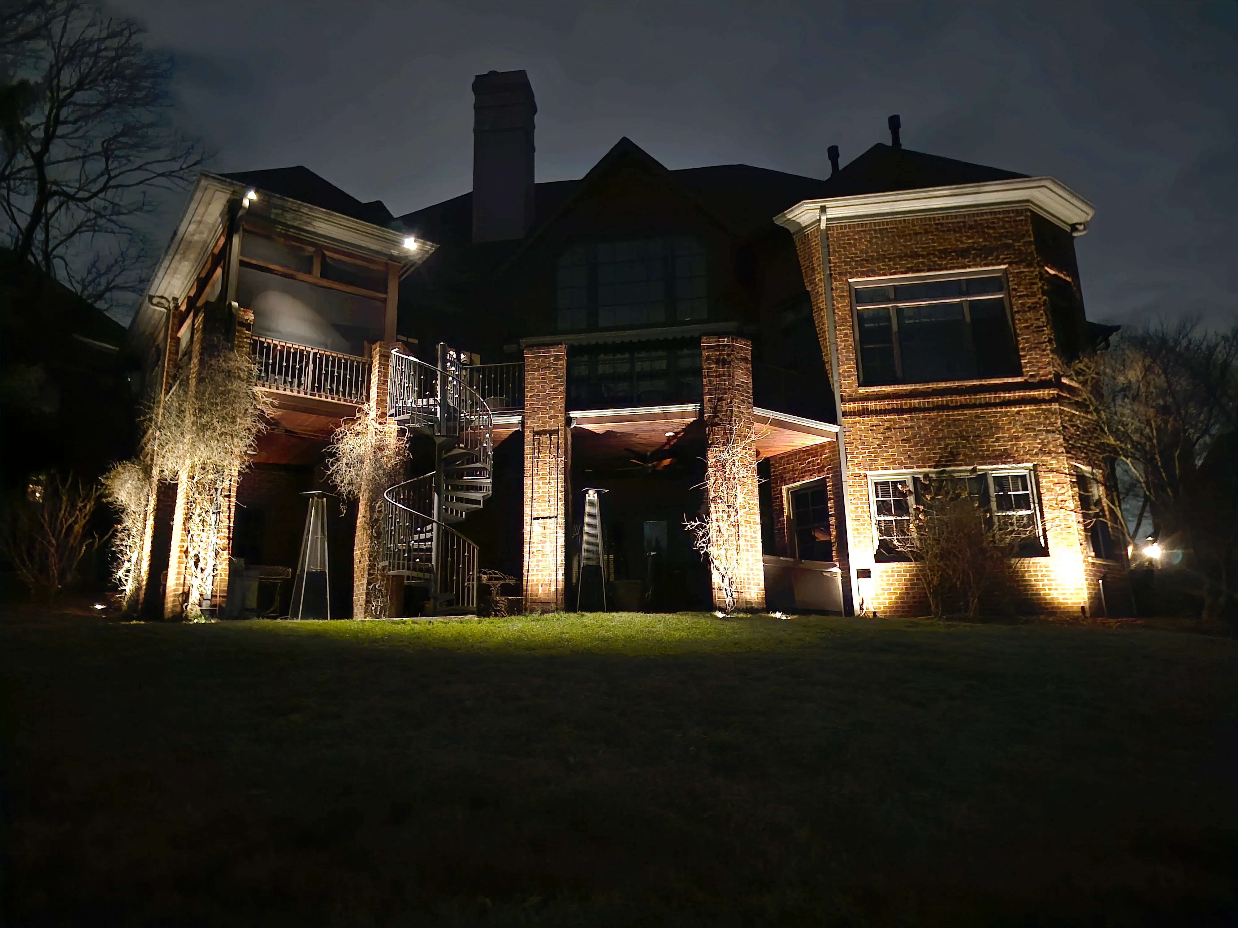 Brick home at night with uplighting on columns and architectural accent lighting on porches